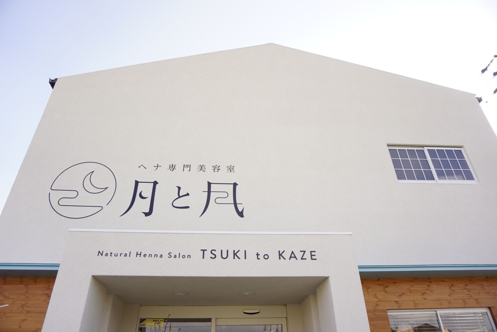 白い外壁に月と風のロゴが入った城東通店の外観